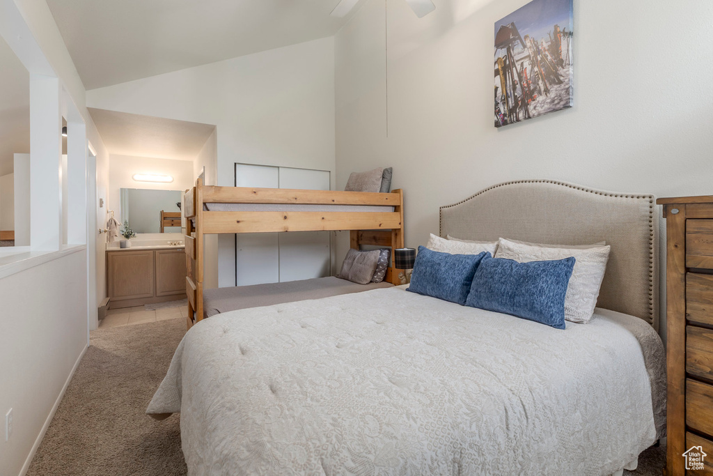 Carpeted bedroom featuring vaulted ceiling, ensuite bath, and baseboards