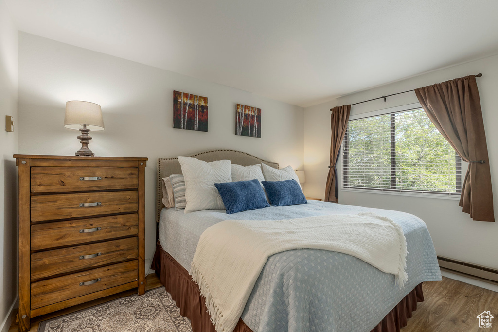 Bedroom featuring wood finished floors and a baseboard heating unit