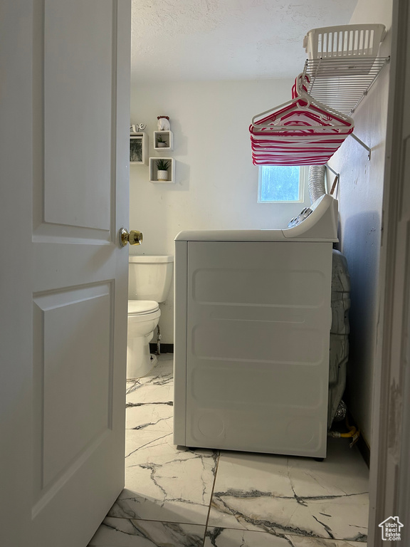 Bathroom featuring marble finish floors, toilet, and washer / clothes dryer