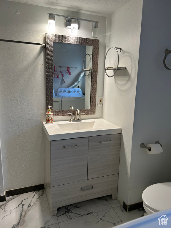 Half bath with marble look tile flooring, baseboards, vanity, and toilet