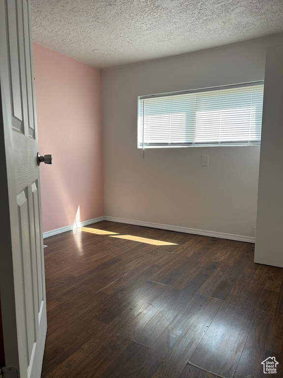 Empty room featuring hardwood / wood-style flooring, baseboards, and a textured ceiling