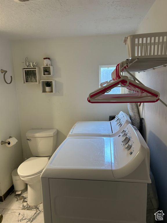 Laundry room featuring washing machine and dryer and a textured ceiling