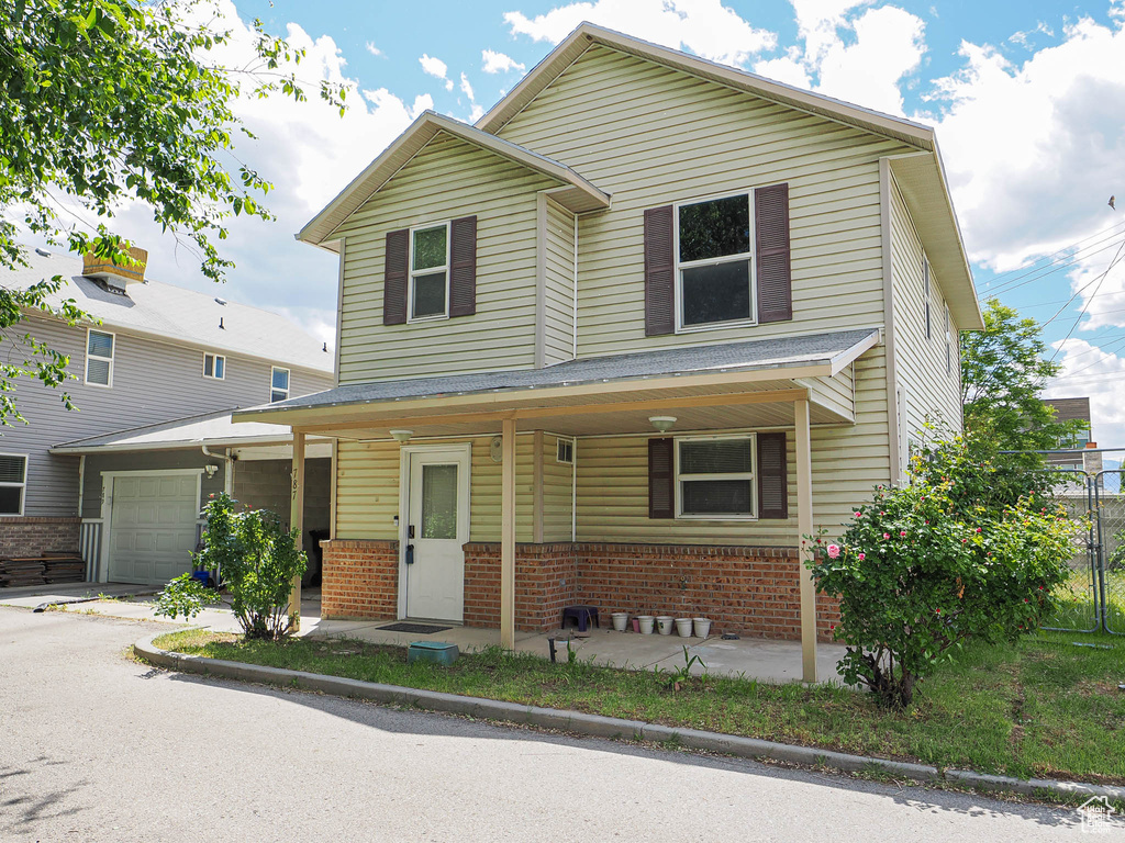 View of front facade with brick siding, a porch, a garage, and concrete driveway