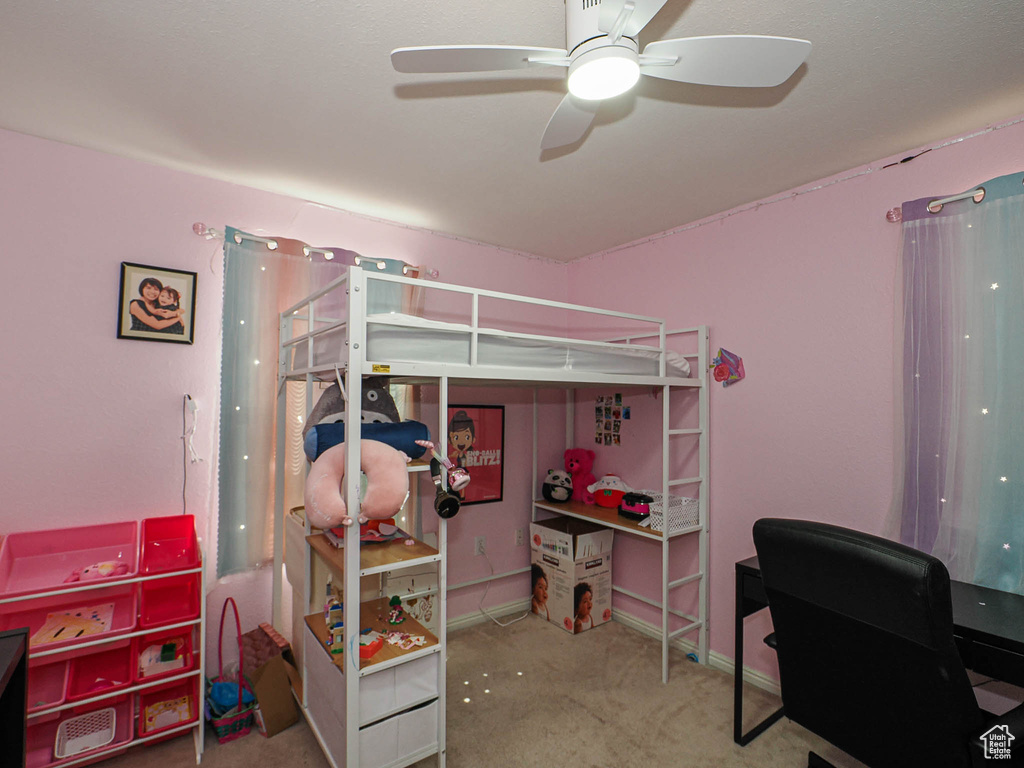 Carpeted bedroom with a desk, baseboards, and a ceiling fan