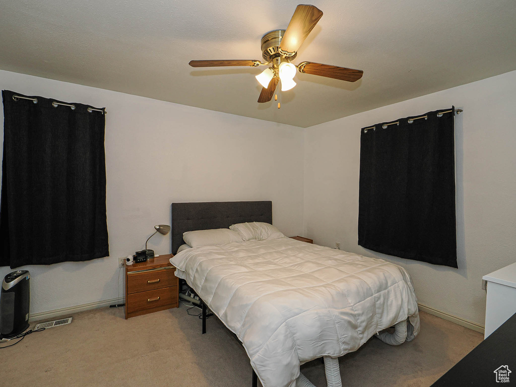 Bedroom with light colored carpet and a ceiling fan
