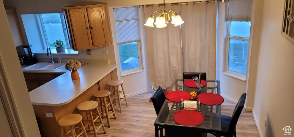 Dining area featuring a chandelier, light wood finished floors, healthy amount of natural light, and baseboards