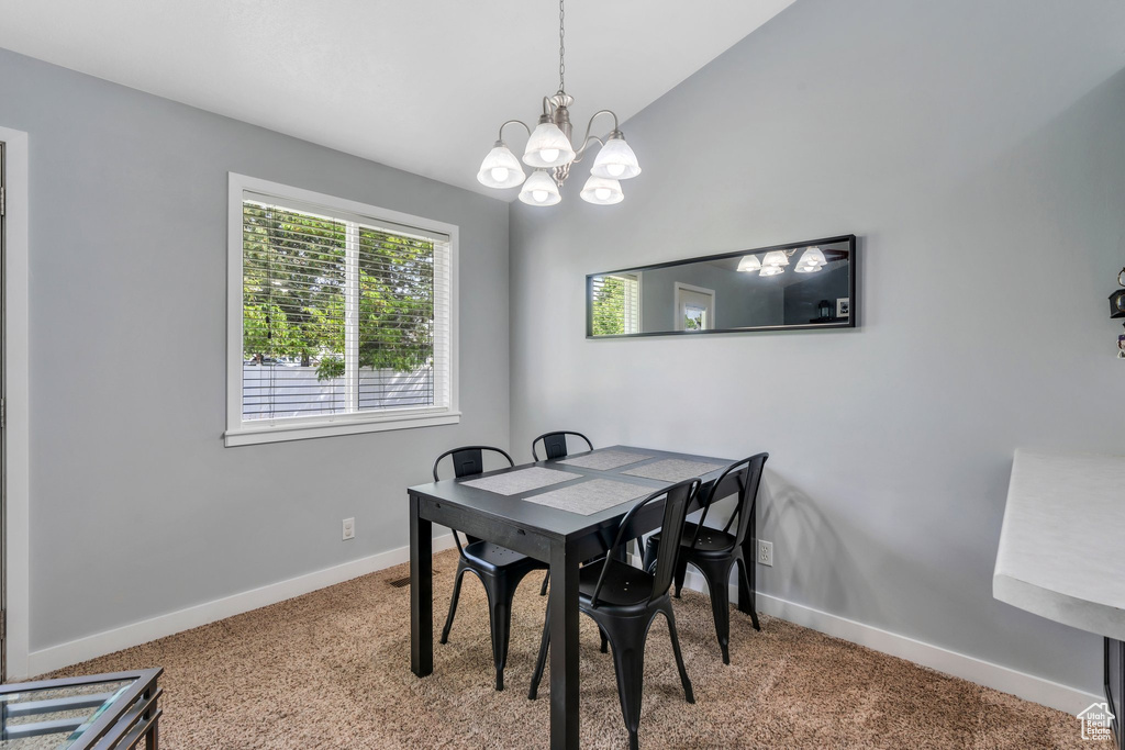 Carpeted dining area featuring baseboards, a chandelier, and vaulted ceiling
