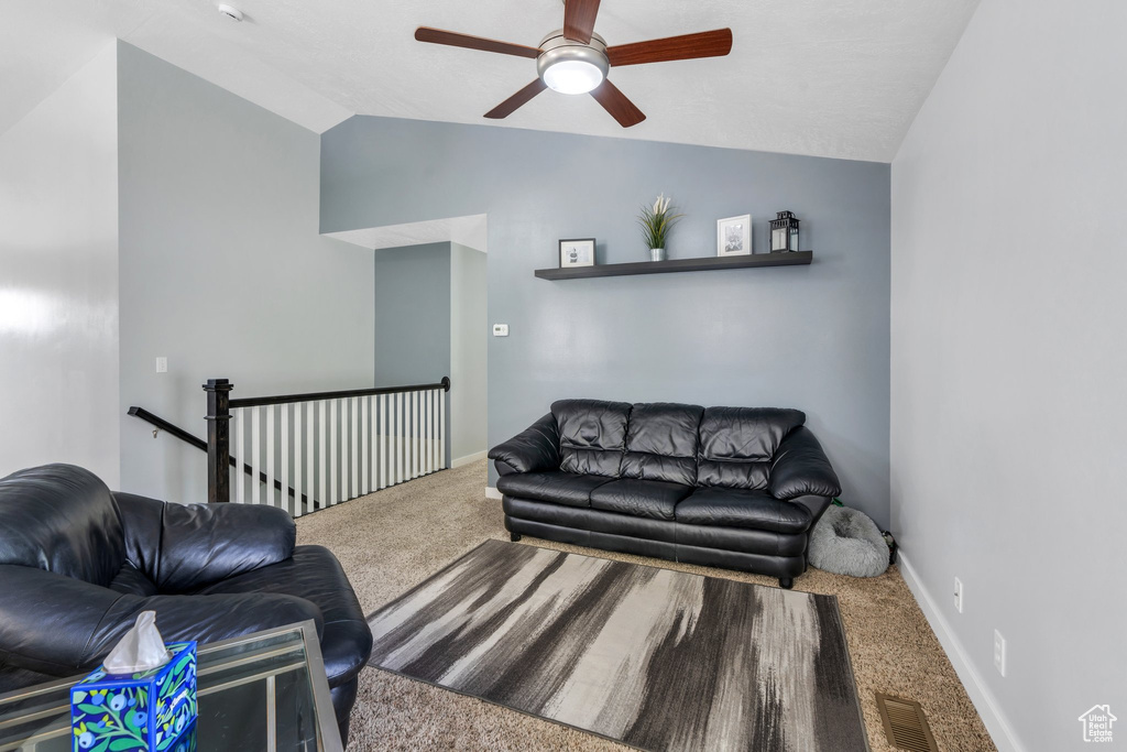 Carpeted living area with ceiling fan, vaulted ceiling, and baseboards