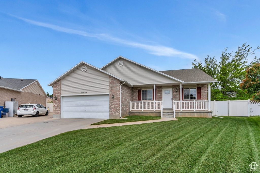 Ranch-style house featuring a porch, driveway, brick siding, and a garage