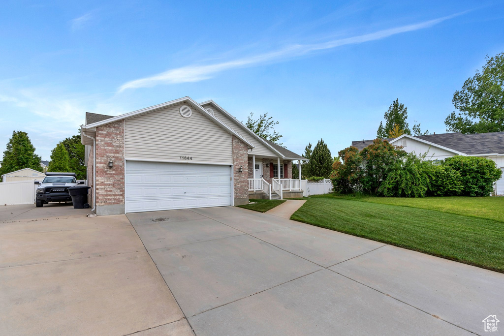 Single story home with concrete driveway, a porch, a front lawn, brick siding, and an attached garage