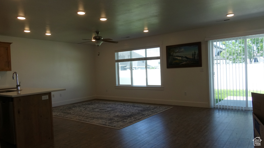 Unfurnished living room featuring a sink, baseboards, dark wood-style flooring, a ceiling fan, and recessed lighting