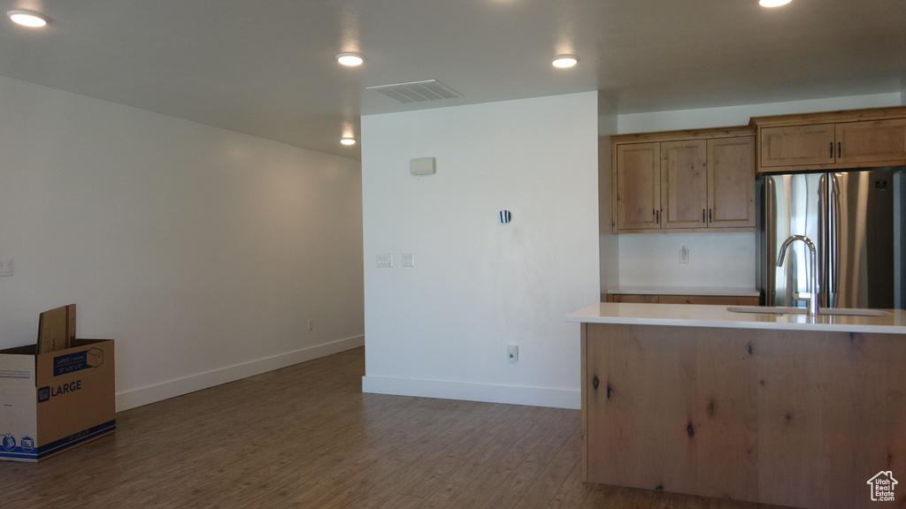 Kitchen with freestanding refrigerator, baseboards, wood finished floors, light countertops, and a sink