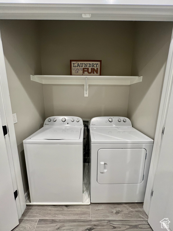 Laundry room with washer and clothes dryer and wood finished floors