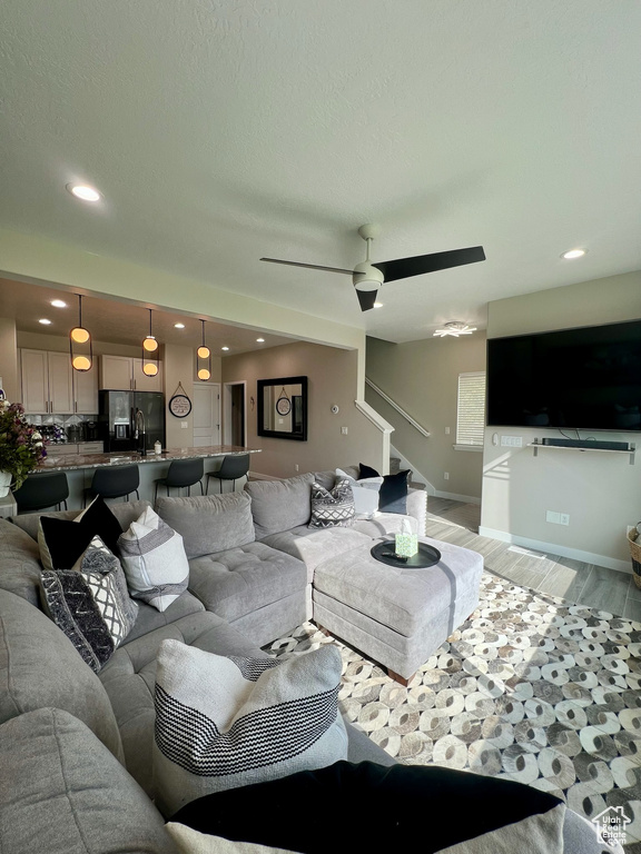 Living area featuring stairway, light wood finished floors, recessed lighting, ceiling fan, and baseboards