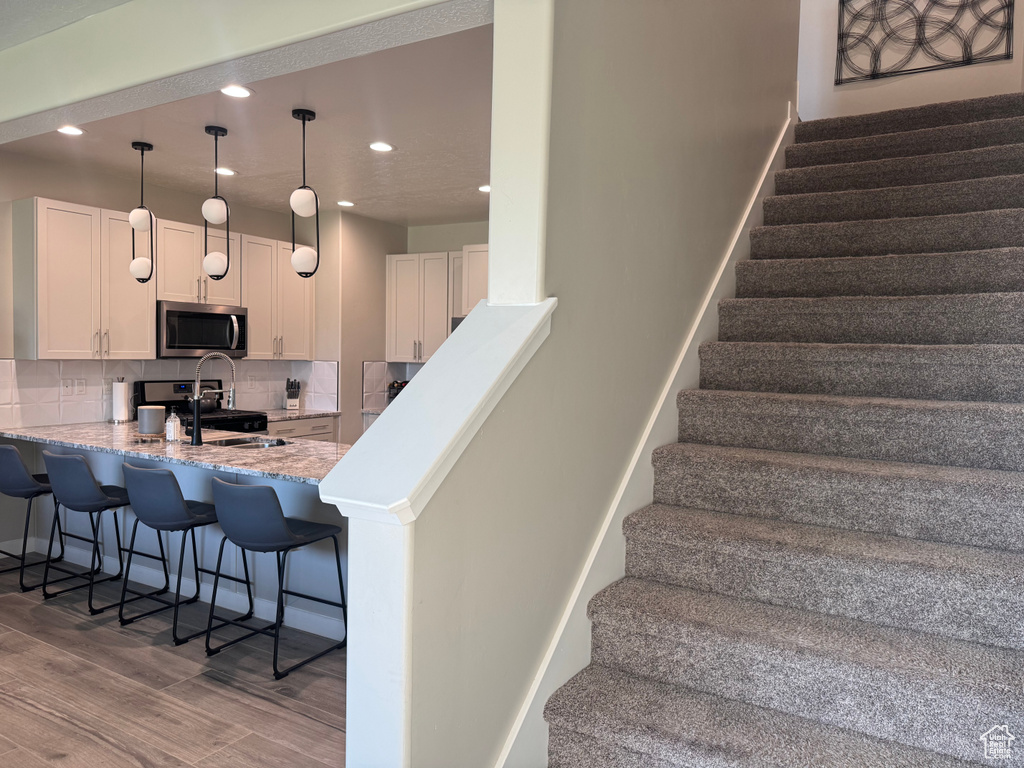 Stairs with wood finished floors and recessed lighting