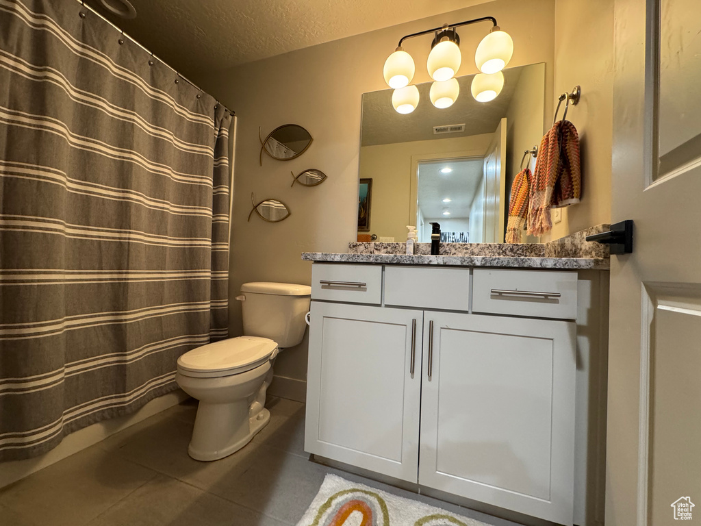 Full bathroom featuring vanity, a textured ceiling, a shower with curtain, and tile patterned floors
