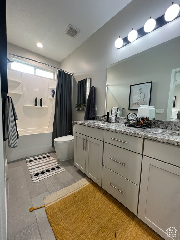 Bathroom featuring shower / tub combo with curtain, vanity, and toilet