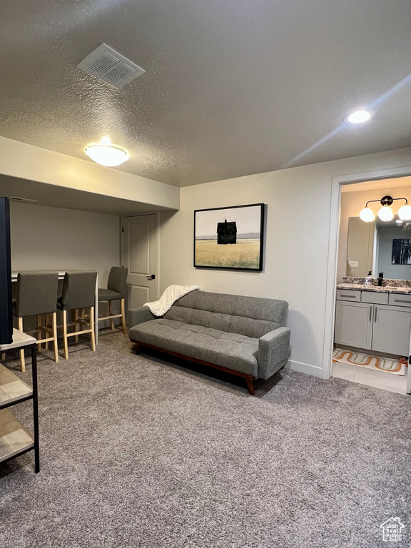 Carpeted living area featuring a textured ceiling, baseboards, bar area, and recessed lighting