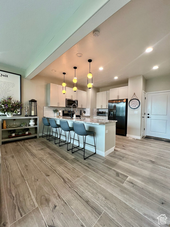Kitchen with black fridge, light wood-style flooring, stainless steel microwave, a peninsula, and recessed lighting