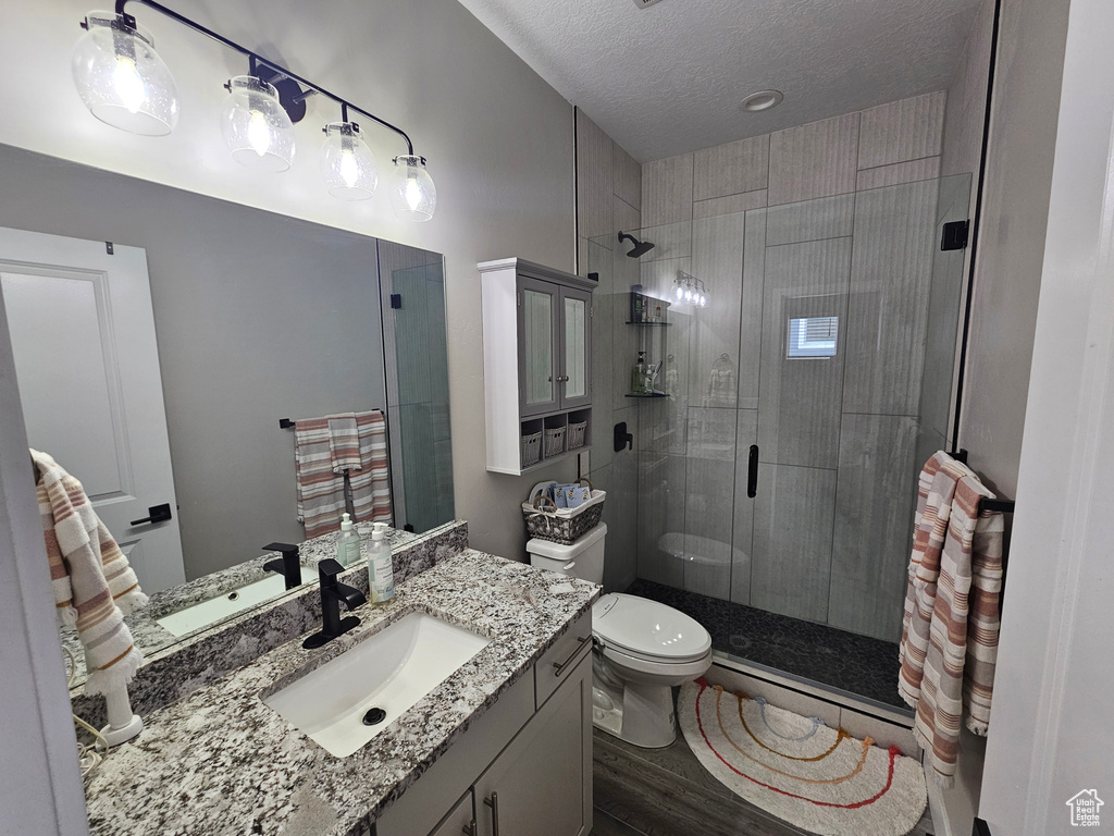 Full bathroom featuring a stall shower, vanity, and a textured ceiling