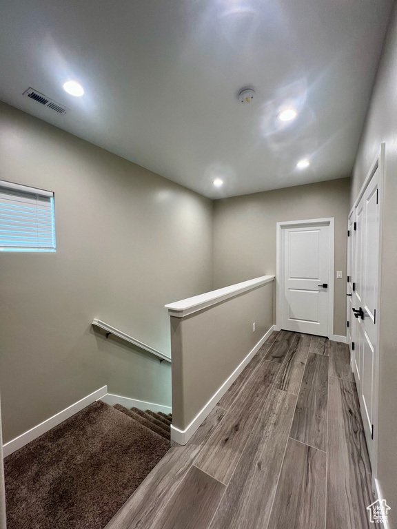 Hallway featuring an upstairs landing, wood finished floors, baseboards, and recessed lighting