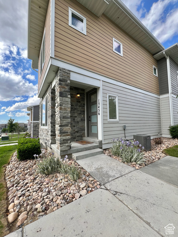 Entrance to property with central AC and stone siding