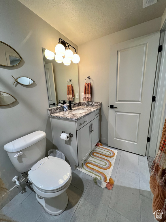 Bathroom featuring vanity, toilet, and a textured ceiling