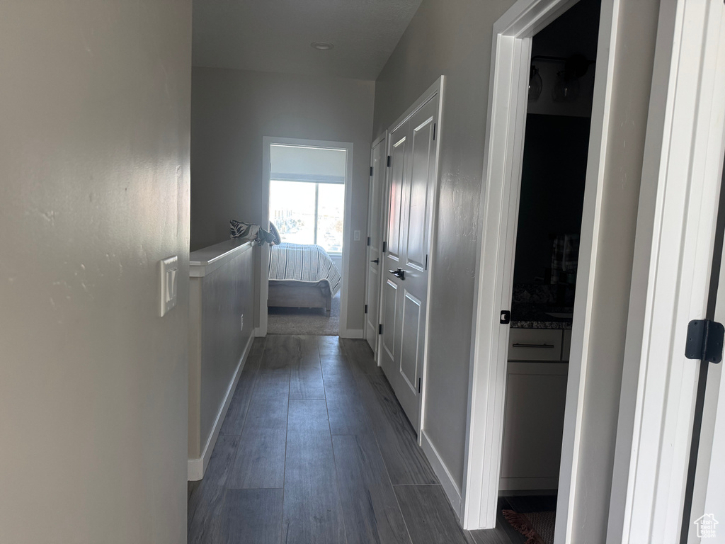 Corridor with dark wood-type flooring and baseboards
