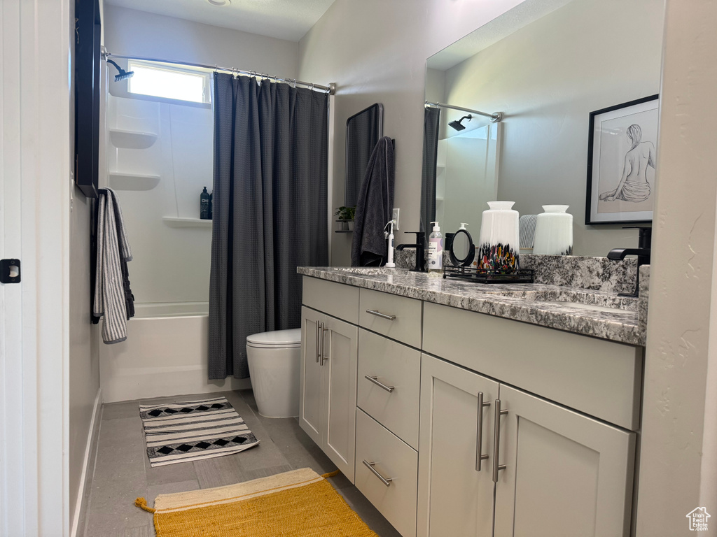 Bathroom with vanity, shower / bath combo, toilet, and baseboards