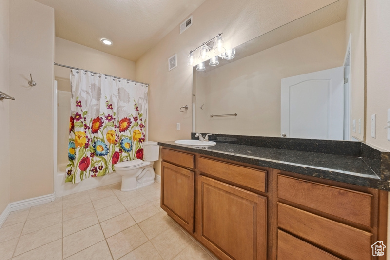 Full bathroom with toilet, tile patterned flooring, vanity, shower / bathtub combination with curtain, and baseboards