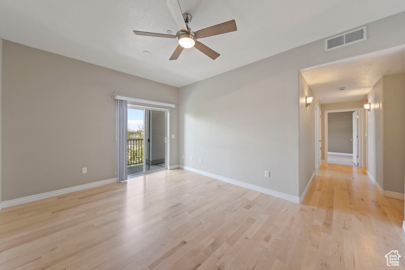 Empty room with a ceiling fan, light wood-style flooring, and baseboards