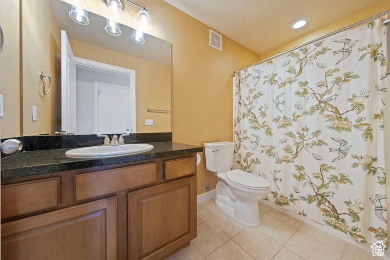Bathroom featuring tile patterned floors, toilet, vanity, baseboards, and a shower with shower curtain