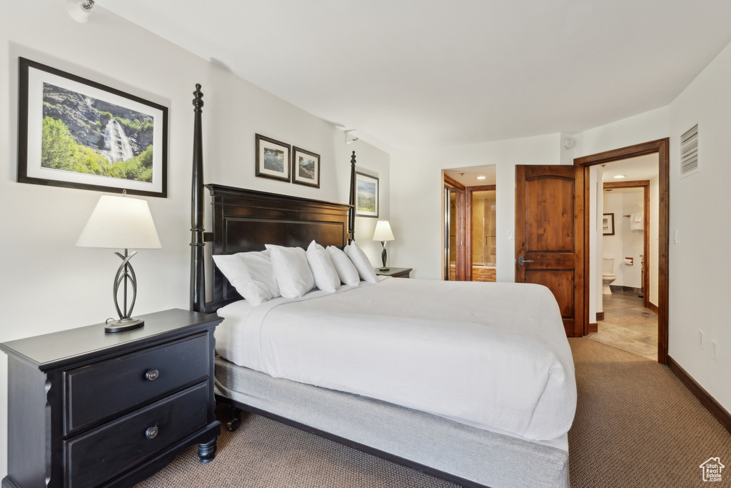 Bedroom with light carpet, connected bathroom, and baseboards