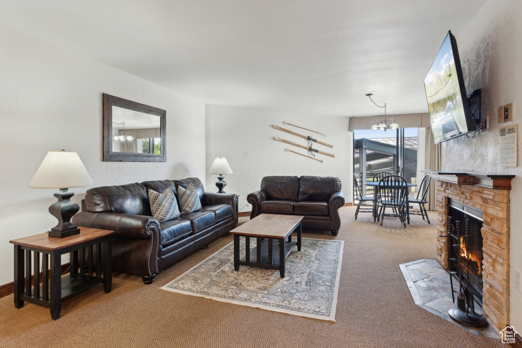 Living area with carpet flooring, a chandelier, and a fireplace
