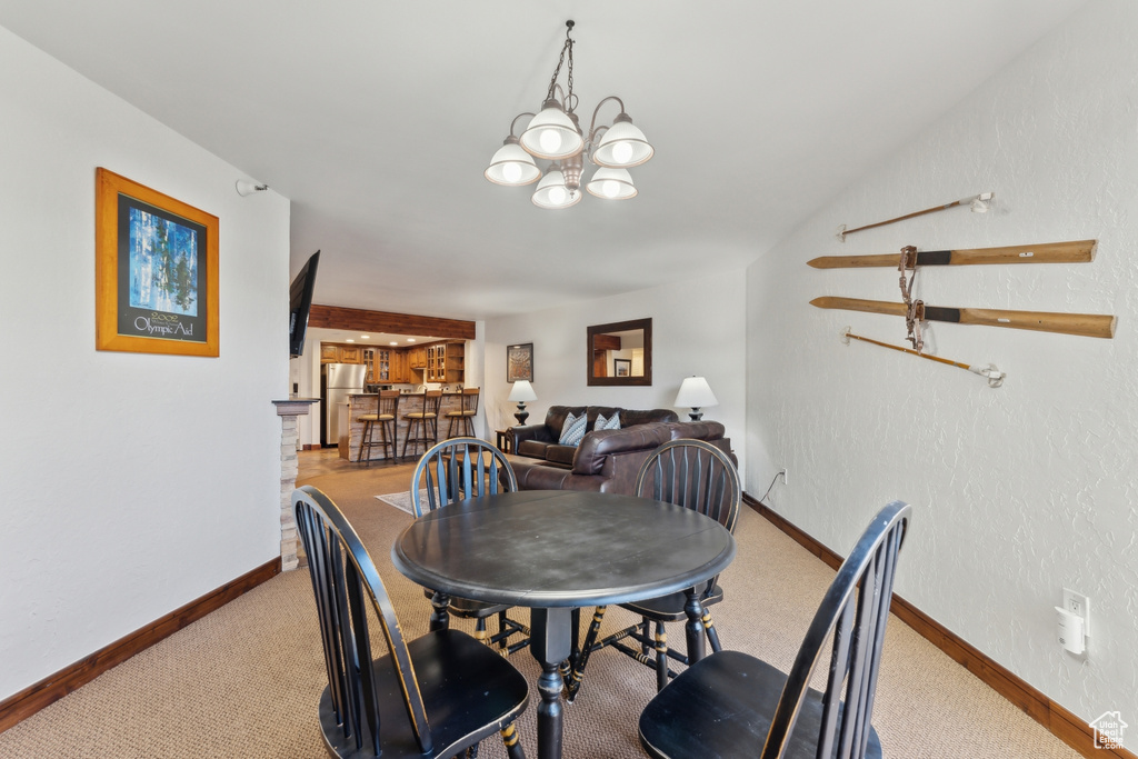 Carpeted dining area with baseboards and a chandelier