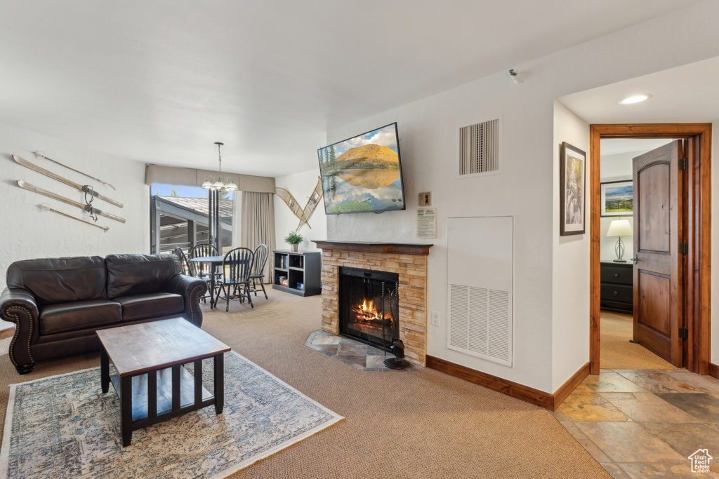 Living area featuring a fireplace, carpet, a chandelier, and baseboards