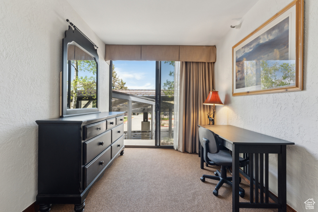 Carpeted home office featuring a textured wall