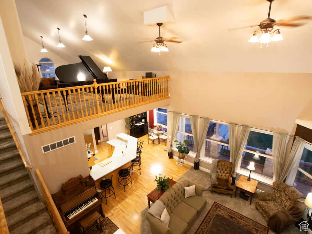Living room featuring a ceiling fan, wood finished floors, stairs, and high vaulted ceiling