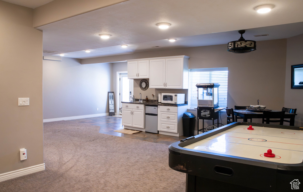 Recreation room featuring a sink, baseboards, and dark colored carpet