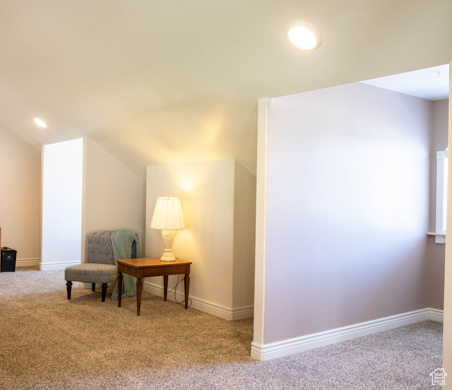Living area with carpet, vaulted ceiling, and baseboards