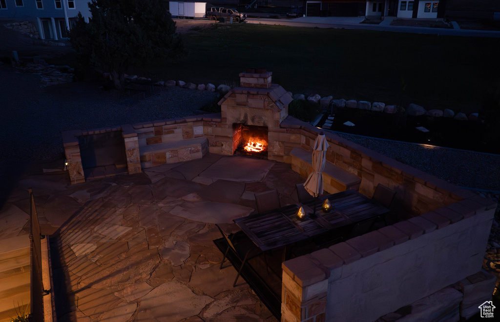 Patio at twilight featuring an outdoor stone fireplace, a patio area, and a fire pit