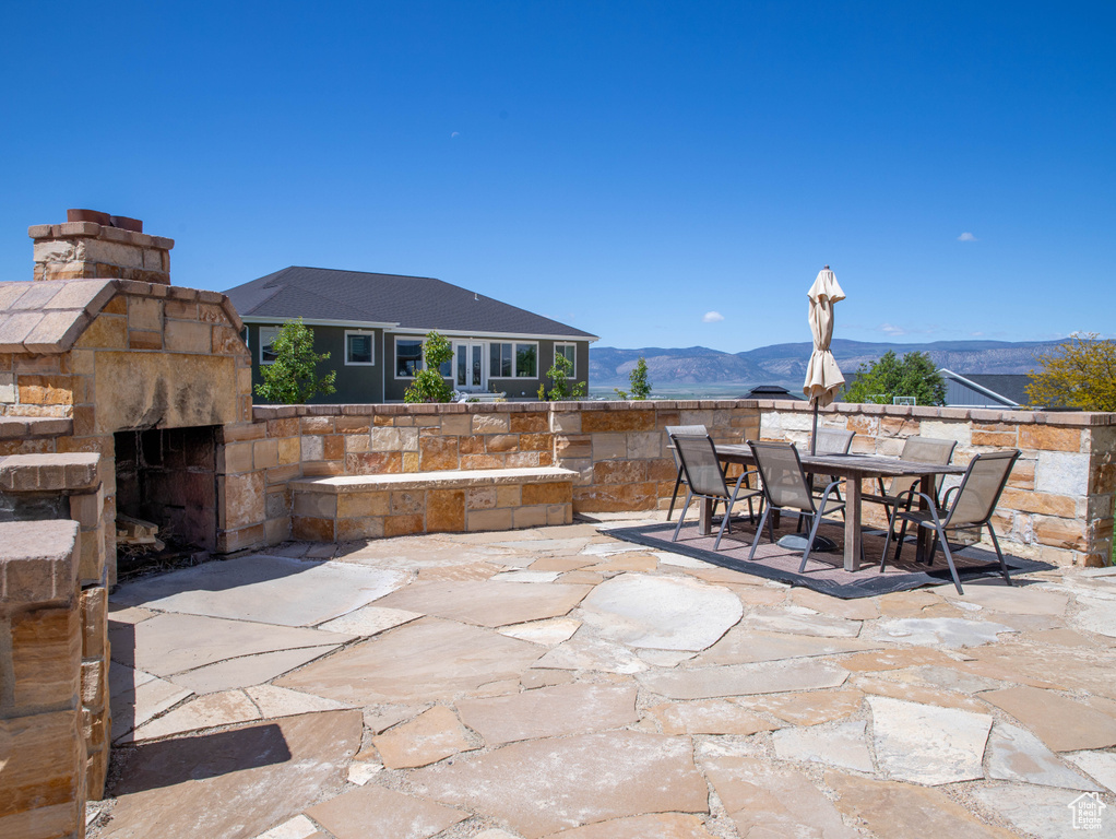 View of patio / terrace with outdoor dining area, a mountain view, and an outdoor stone fireplace