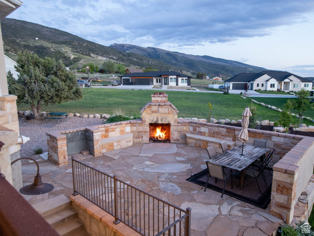 View of patio featuring a mountain view, an outdoor stone fireplace, and outdoor dining space