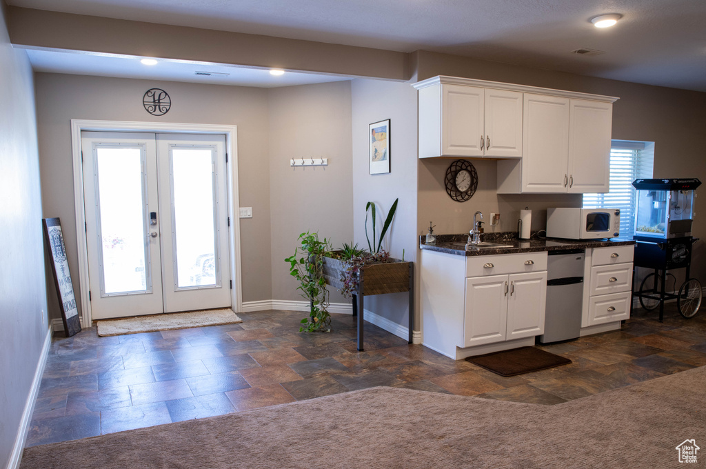 Kitchen featuring french doors, white microwave, stone finish floors, and baseboards