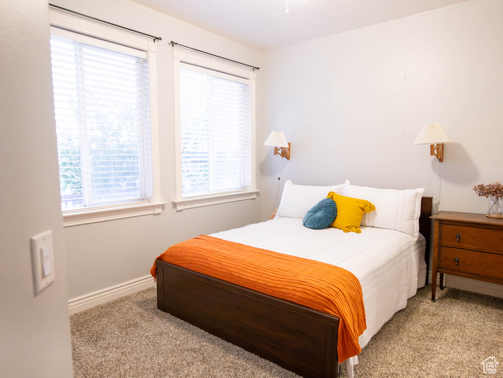 Carpeted bedroom featuring multiple windows and baseboards