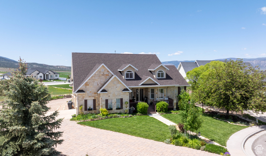 View of front of property featuring stone siding, a porch, a front yard, and a mountain view