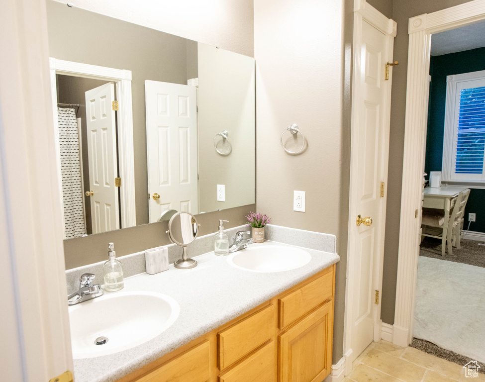 Bathroom featuring double vanity, tile patterned floors, and baseboards