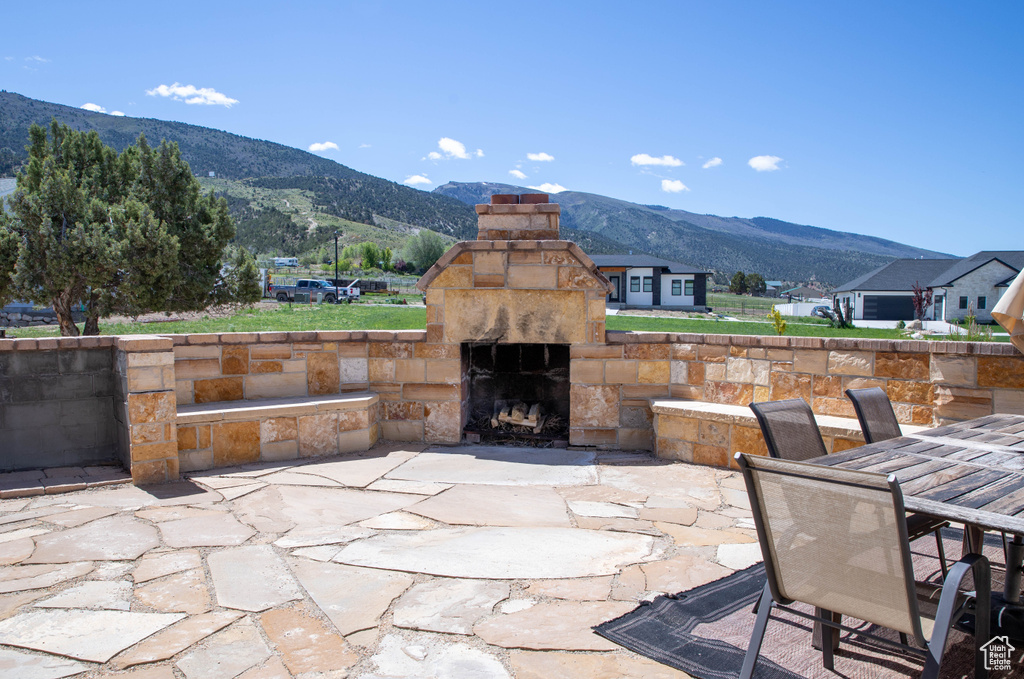 View of patio / terrace with an outdoor stone fireplace, a mountain view, and outdoor dining space