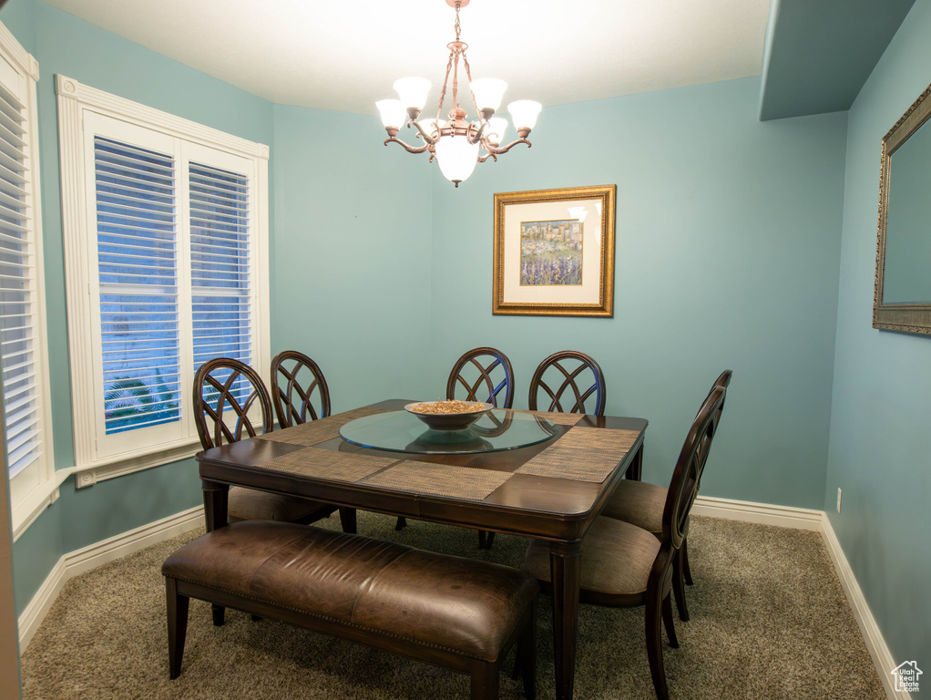 Dining space featuring carpet floors, a chandelier, and baseboards