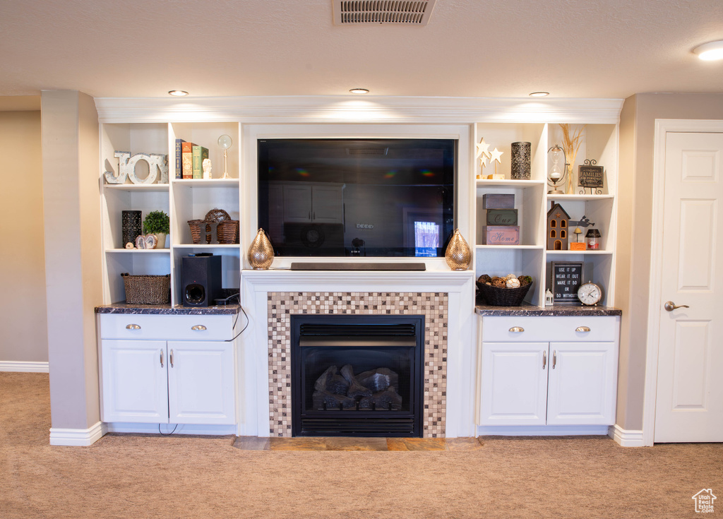 Carpeted living area featuring baseboards and a tiled fireplace